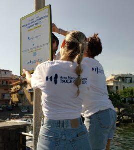 I volontari del Servizio Civile posizionano un cartello indicativo dell'Area Marina Protetta